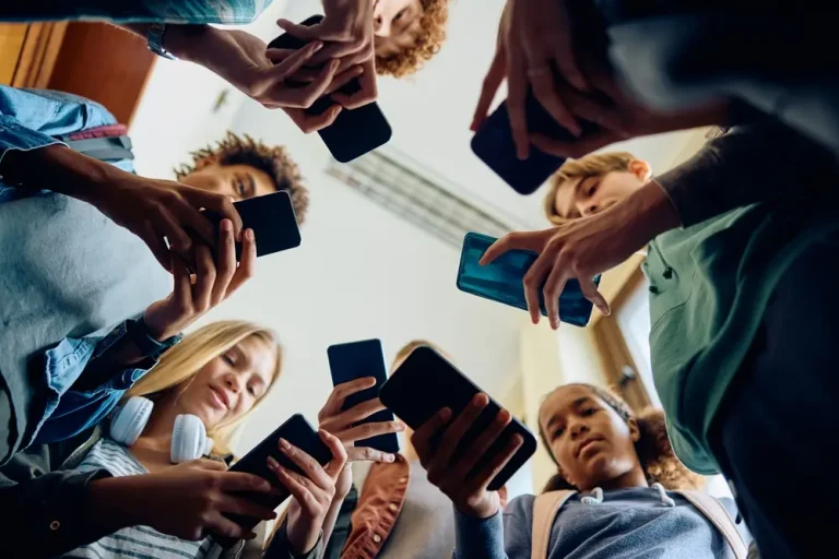 Low-angle view of high school students using their mobile phones.