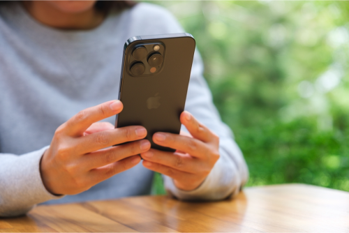 Une femme tenant et utilisant un smartphone Iphone 15 Pro Max,